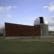 A small observatory building with a dome-shaped roof and a wooden exterior wall stands on a grassy area under a partly cloudy sky.