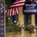 Exterior of a brick building with an American flag, window boxes displaying vibrant flowers, and signs reading "Fine American Crafts," "Jewelry," "Prints & Paintings," "Pottery," "Glass," and "Mountain Laurel Gallery.