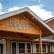 A building features a sign with the name "Charlotte's Cafe" on a wooden peaked roof. The facade has large windows and a covered porch. The sky is partly cloudy, suggesting a bright day.